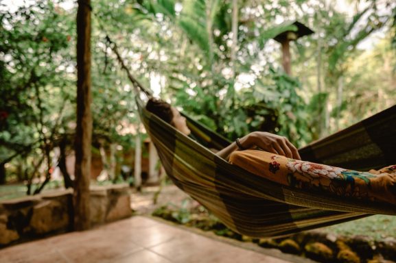 Footer Person relaxing in a hammock surrounded by lush greenery.