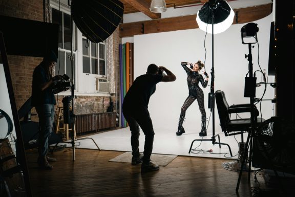 A model poses dramatically in a studio while a photographer captures the shot.